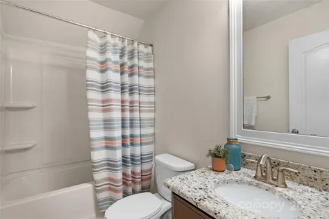 a bathroom with a granite countertop sink toilet mirror and shower