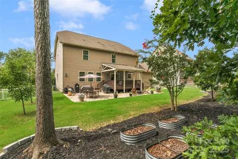 a view of a backyard with table and chairs potted plants and large tree