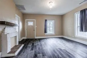 an empty room with wooden floor a fireplace and windows