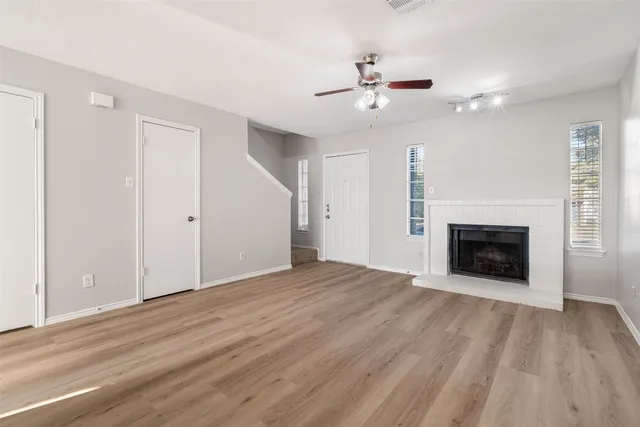 a view of an empty room with wooden floor fireplace and a window