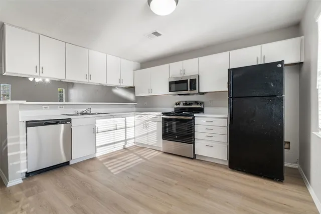 a kitchen with a refrigerator stove and white cabinets
