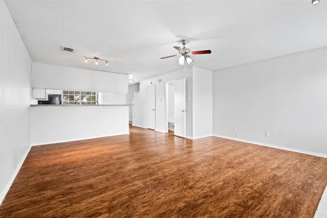 a view of empty room with wooden floor and ceiling fan