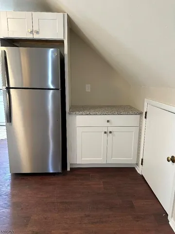 a view of a refrigerator in kitchen and white cabinets