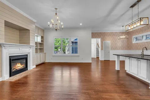a view of an empty room with wooden floor fireplace and a window