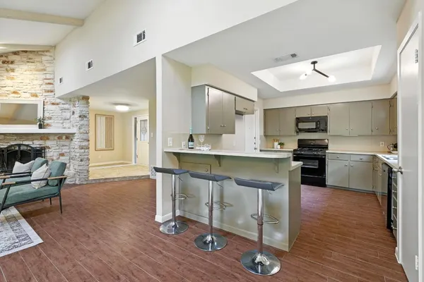 a kitchen with kitchen island granite countertop a stove a sink cabinets and wooden floor
