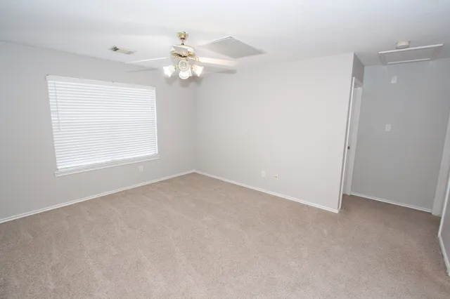 an empty room with windows and chandelier fan