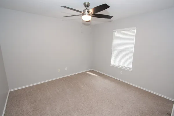 an empty room with a window and a fan