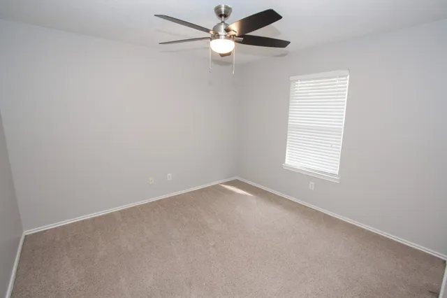 an empty room with a window and a fan