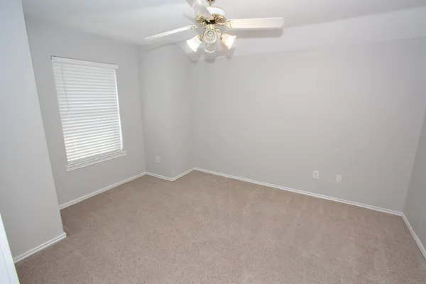 an empty room with a window and a fan