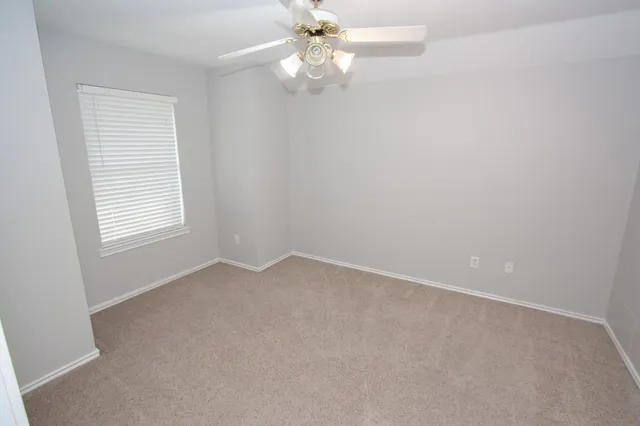 an empty room with a window and a fan