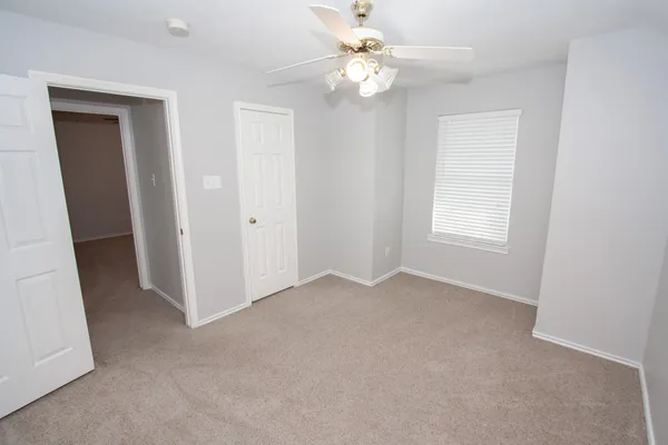 an empty room with windows and fan