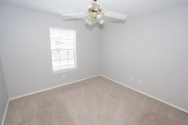 an empty room with a window and a fan