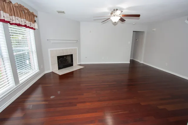 a view of a livingroom with a fireplace a ceiling fan and wooden floor