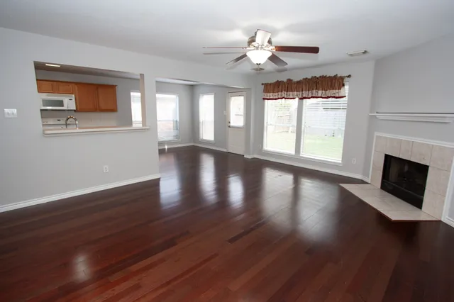 a view of an empty room with wooden floor and a window