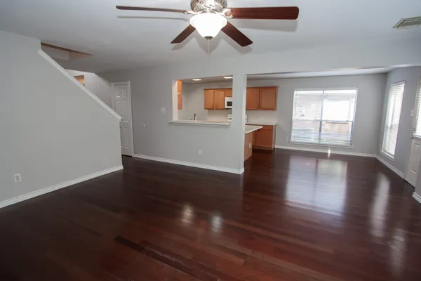 a view of an empty room with wooden floor and a window