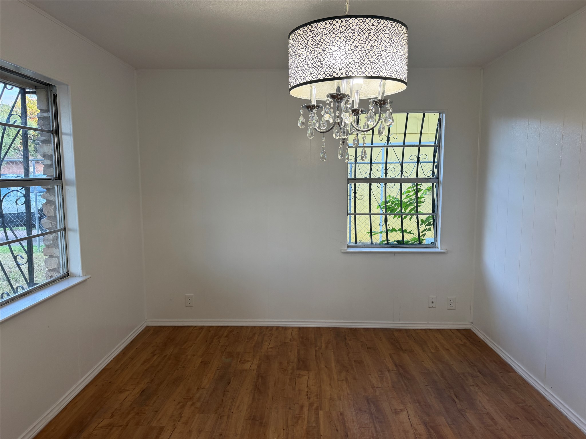 1060 Gardner Road Austin, TX 78721 - Photo 14 of 19 A well-lit room features laminate wood flooring and a distinctive chandelier for modern elegance.