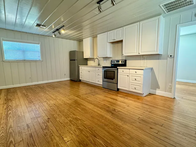 a large kitchen with stainless steel appliances granite countertop a stove a sink and a refrigerator