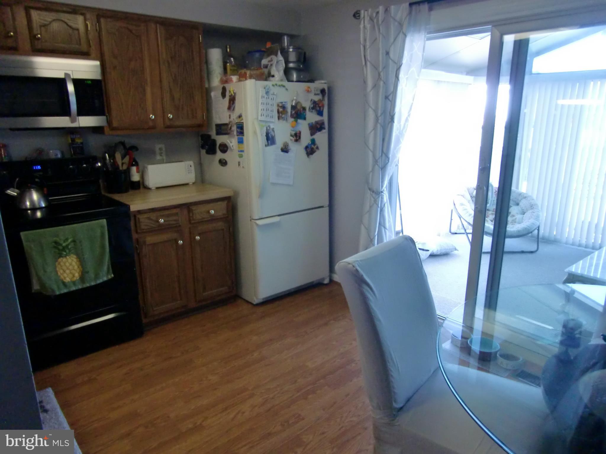 2236 Riding Crop Way Baltimore, MD 21244 - Photo 8 of 25 a kitchen with stainless steel appliances granite countertop a refrigerator a stove a microwave oven with a dining table and chairs with wooden floor