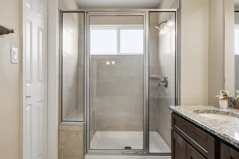 a bathroom with a granite countertop sink a mirror and a shower