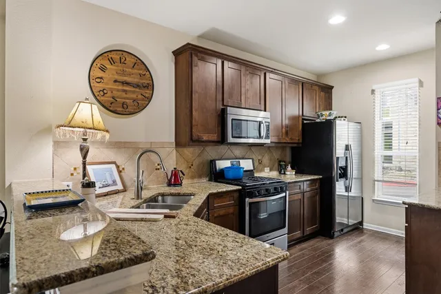 a kitchen with a refrigerator a stove a sink and a stove with wooden floor
