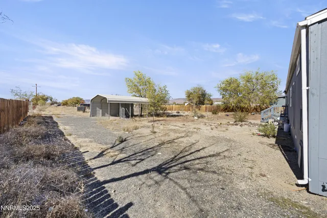 a view of a dry yard with wooden fence