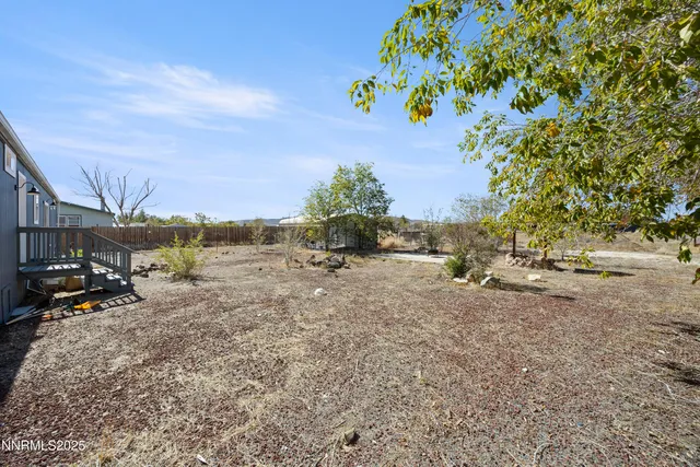 a view of a dry yard with wooden fence