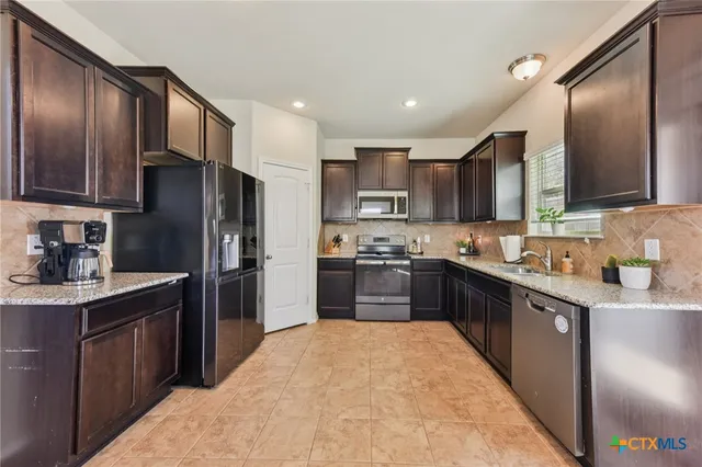 a kitchen with stainless steel appliances granite countertop a refrigerator stove top oven and sink