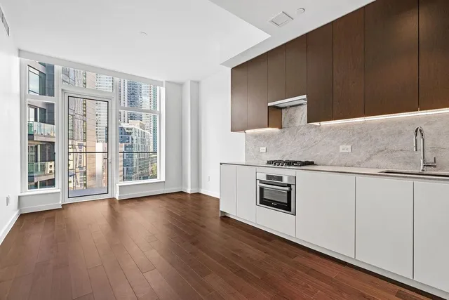 a kitchen with granite countertop a stove top oven a sink and white cabinets with wooden floor