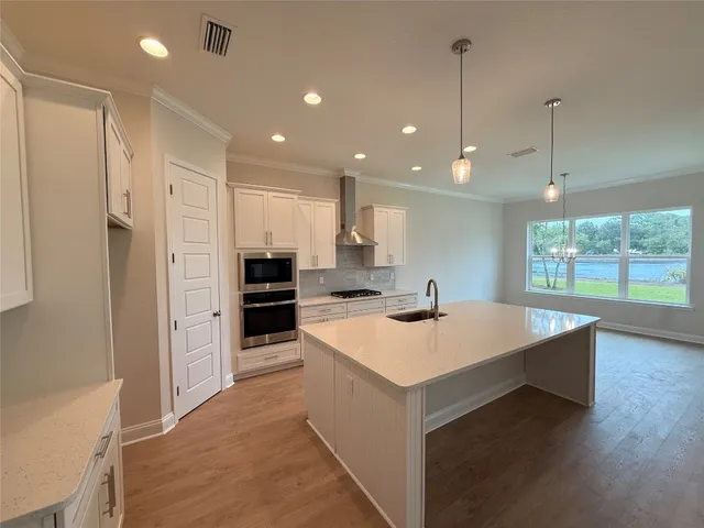 a large kitchen with kitchen island a stove a sink a refrigerator and a wooden floor