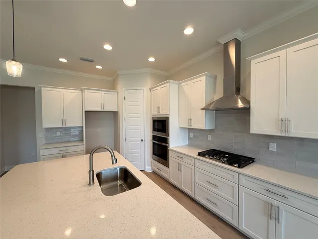 a kitchen with granite countertop a stove a sink a refrigerator and cabinets