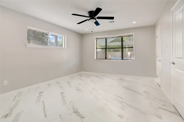 a view of empty room with wooden floor and fan