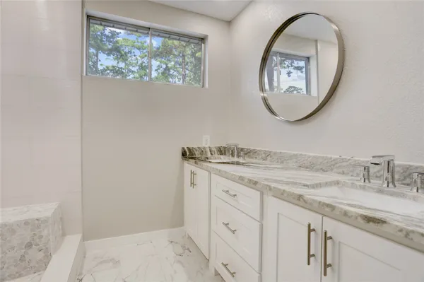 a bathroom with a granite countertop double vanity sink and a mirror
