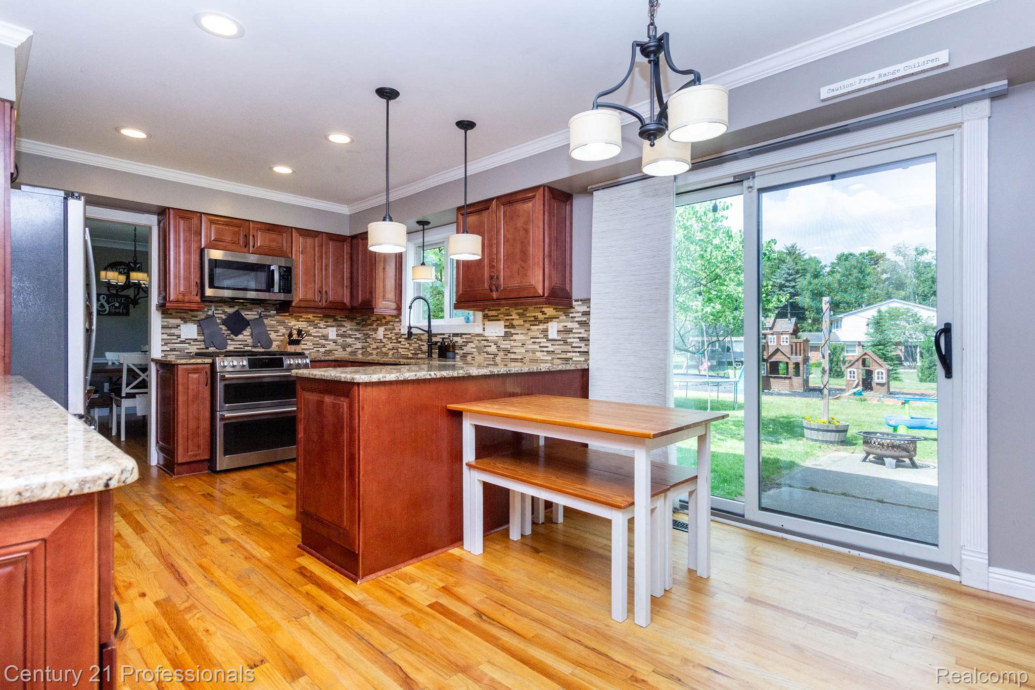 671 Bridgestone Drive Rochester, MI 48309 - Photo 11 of 50 Kitchen featuring wood-finish flooring, custom wood cabinetry, granite countertops, and stainless steel appliances