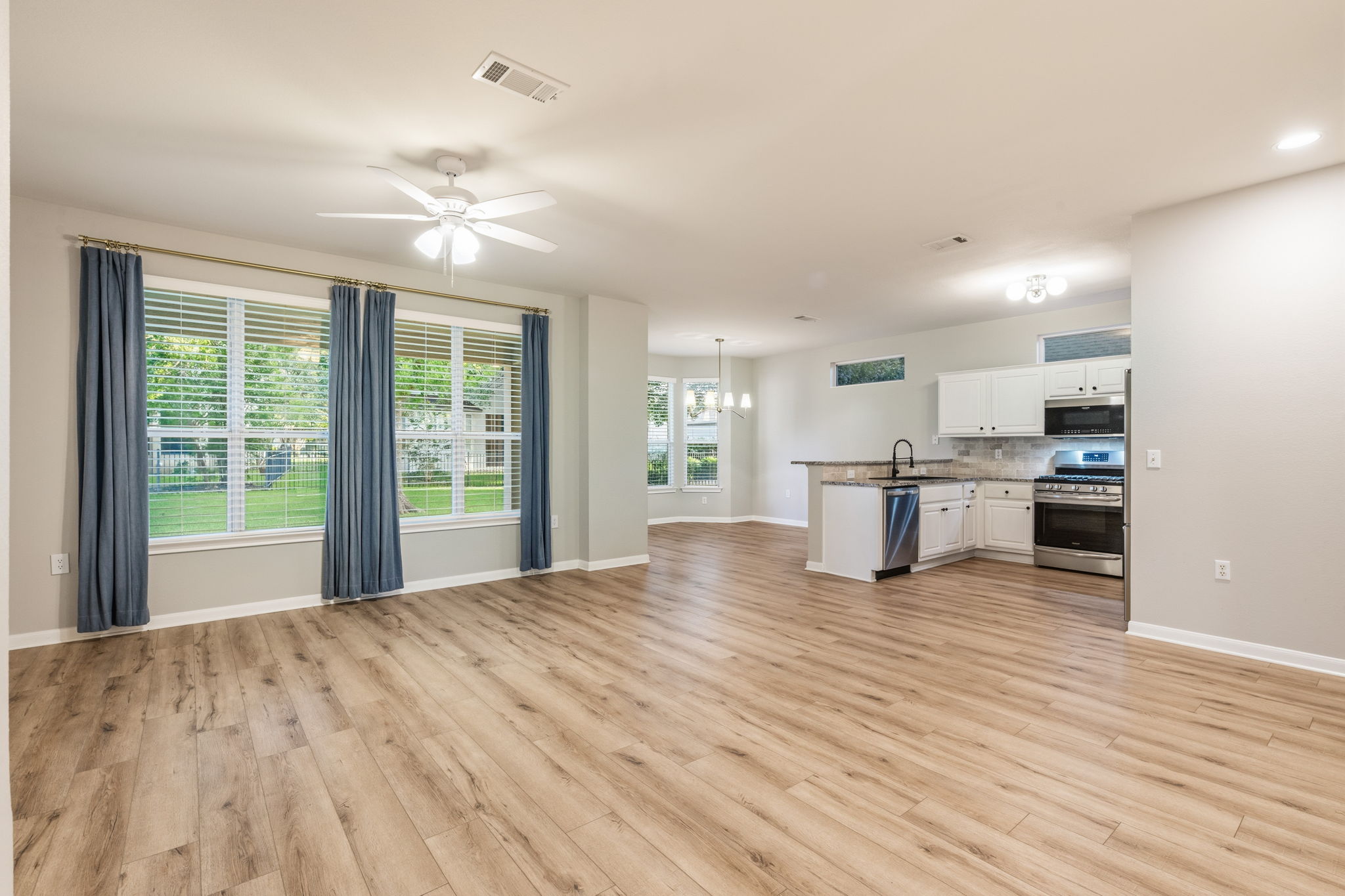 137 Trail Rider Way Georgetown, TX 78633 - Photo 2 of 29 An open-concept interior features wood flooring, a ceiling fan, and a kitchen with stainless steel appliances.