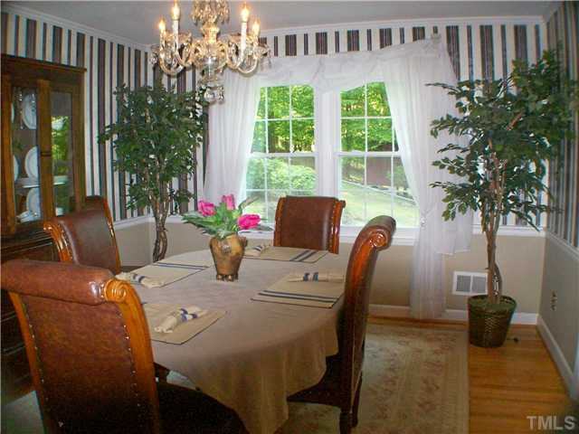 8805 Red Oak Court Raleigh, NC 27613 - Photo 3 of 12 Large and luxurious dining room is complete with hardwood floor, chair rail, crown molding, dimming light fixture and a lovely view. Bring on the guests or enjoy a romantic dinner for two. Fond memories from this comfortable environment will linger on. Dining Room