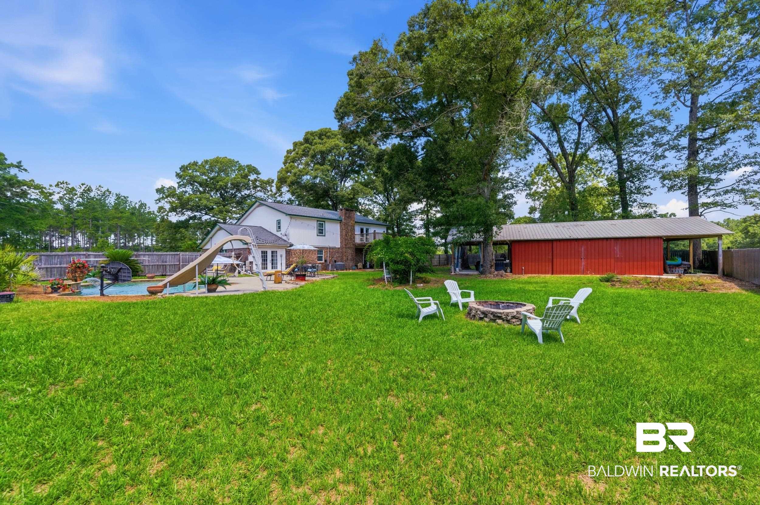 51620 Robert White Road Bay Minette, AL 36507 - Photo 73 of 81 Expansive backyard featuring a manicured lawn, a built-in swimming pool with a waterslide, a brick-clad chimney, a detached red barn, and mature trees