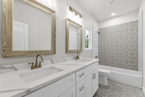 a bathroom with a double vanity sink toilet mirror and bathtub