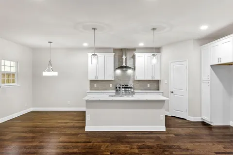 a view of a kitchen with kitchen island a sink wooden floor and living room view