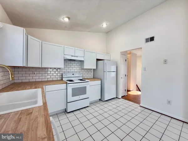 a kitchen with white cabinets and white appliances