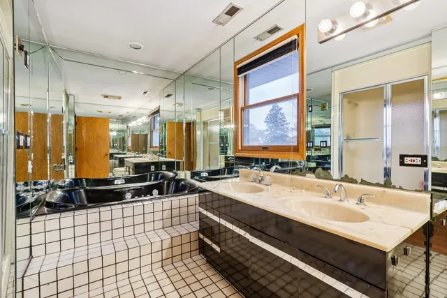 a large bathroom with a double vanity sink a toilet a mirror and shower