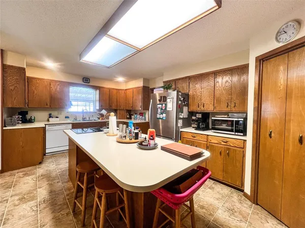 a kitchen with stainless steel appliances kitchen island granite countertop a refrigerator a stove a sink a dining table and chairs with wooden floor
