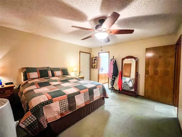 a spacious bedroom with a bed a ceiling fan and a dresser
