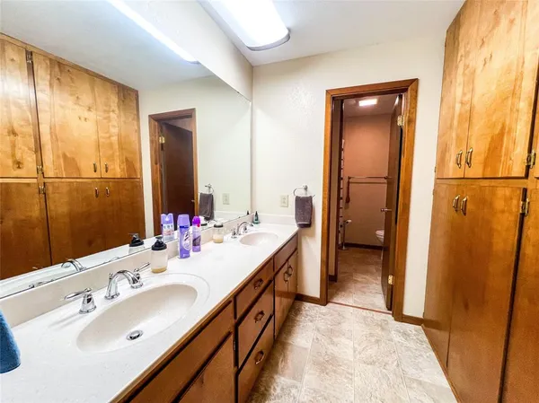 a spacious bathroom with a double vanity sink a mirror and a shower