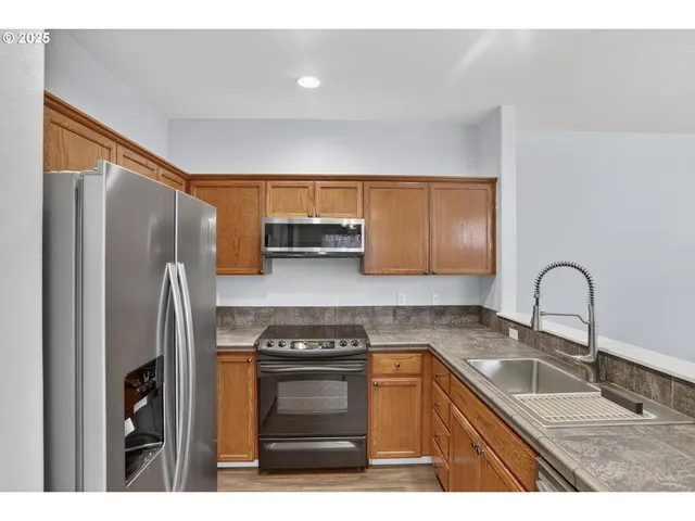 a kitchen with stainless steel appliances granite countertop a refrigerator sink and stove