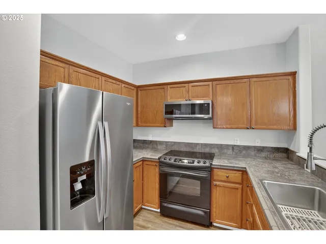 a kitchen with stainless steel appliances granite countertop a refrigerator stove and sink