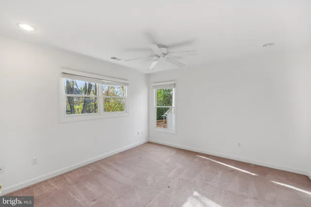 an empty room with windows and ceiling fan