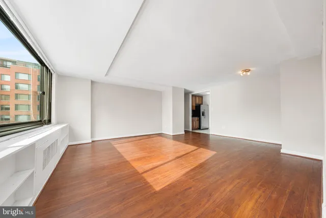a view of an empty room with window and wooden floor