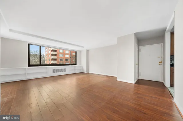 a view of an empty room with wooden floor and a window