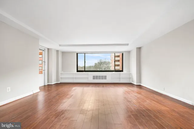a view of an empty room with wooden floor and a window