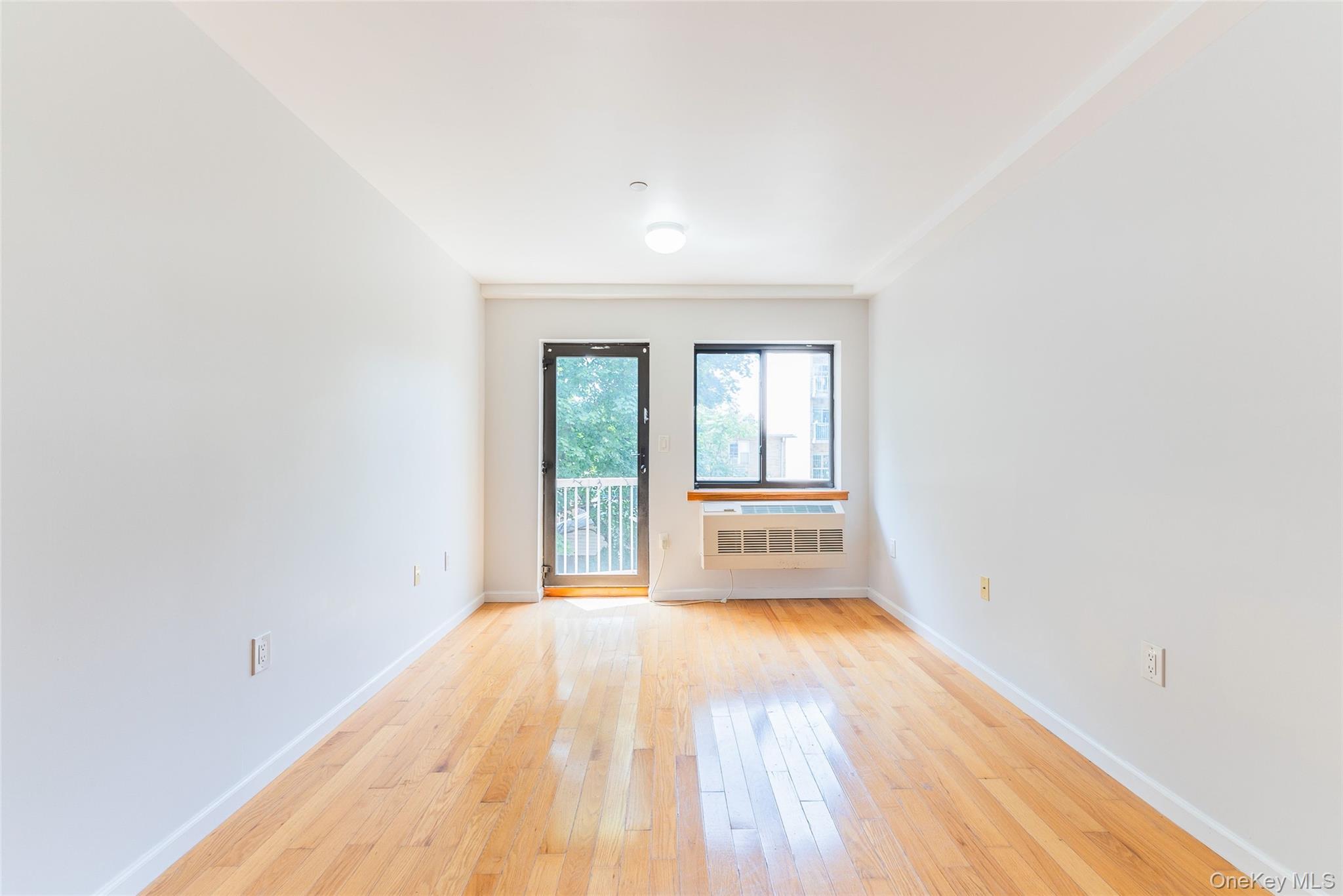 112-26 38th Avenue, Unit 4A Queens, NY 11368 - Photo 10 of 18 an empty room with wooden floor and windows